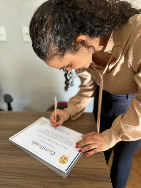 Leticia escrevendo sobre uma mesa em um registro dos bastidores.