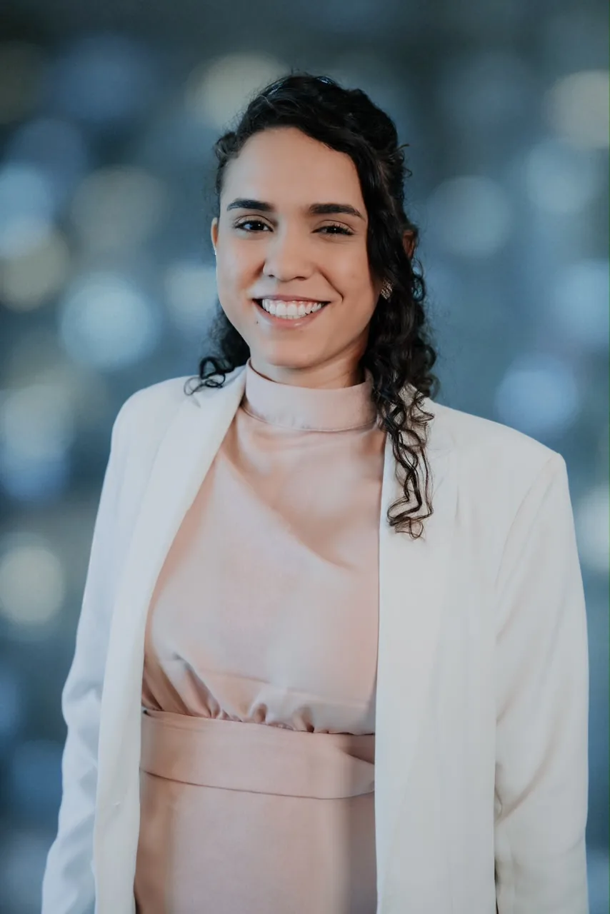 Retrato da Dr. Leticia R. Cavalcante sorrindo, de blazer branco e blusa rosé.