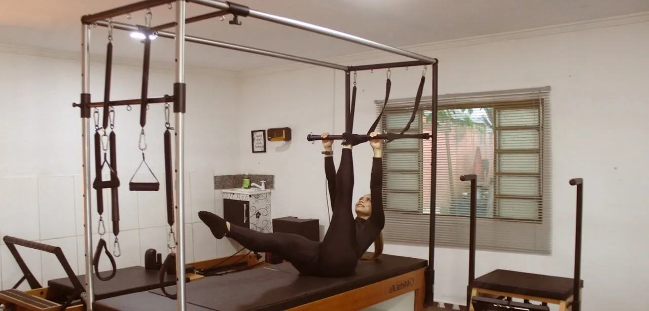 Vista do estúdio com uma pessoa realizando movimento no Cadillac de Pilates.