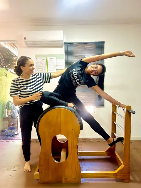 Leticia acompanhando um alongamento lateral no barril de Pilates.