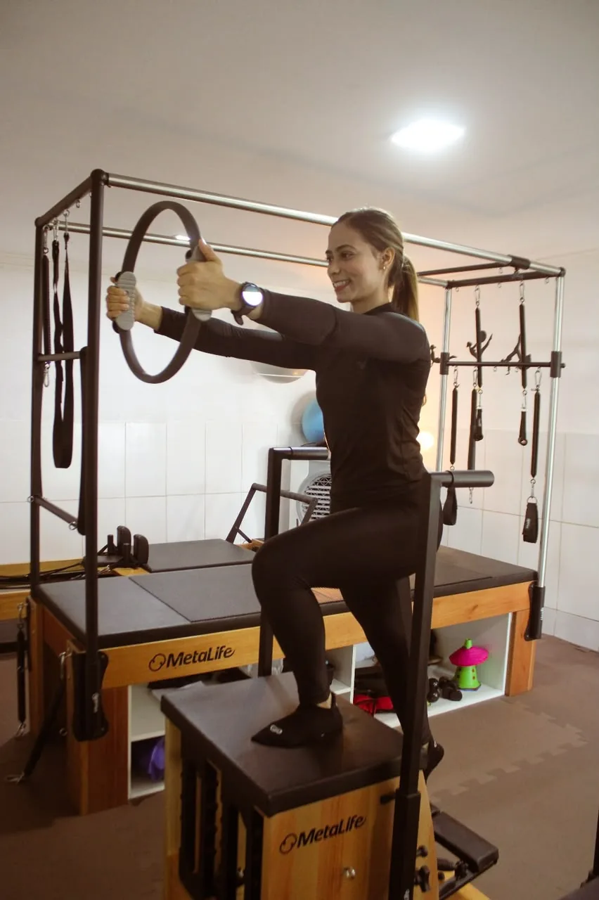 Prática de Pilates com aro e apoio no equipamento do estúdio.